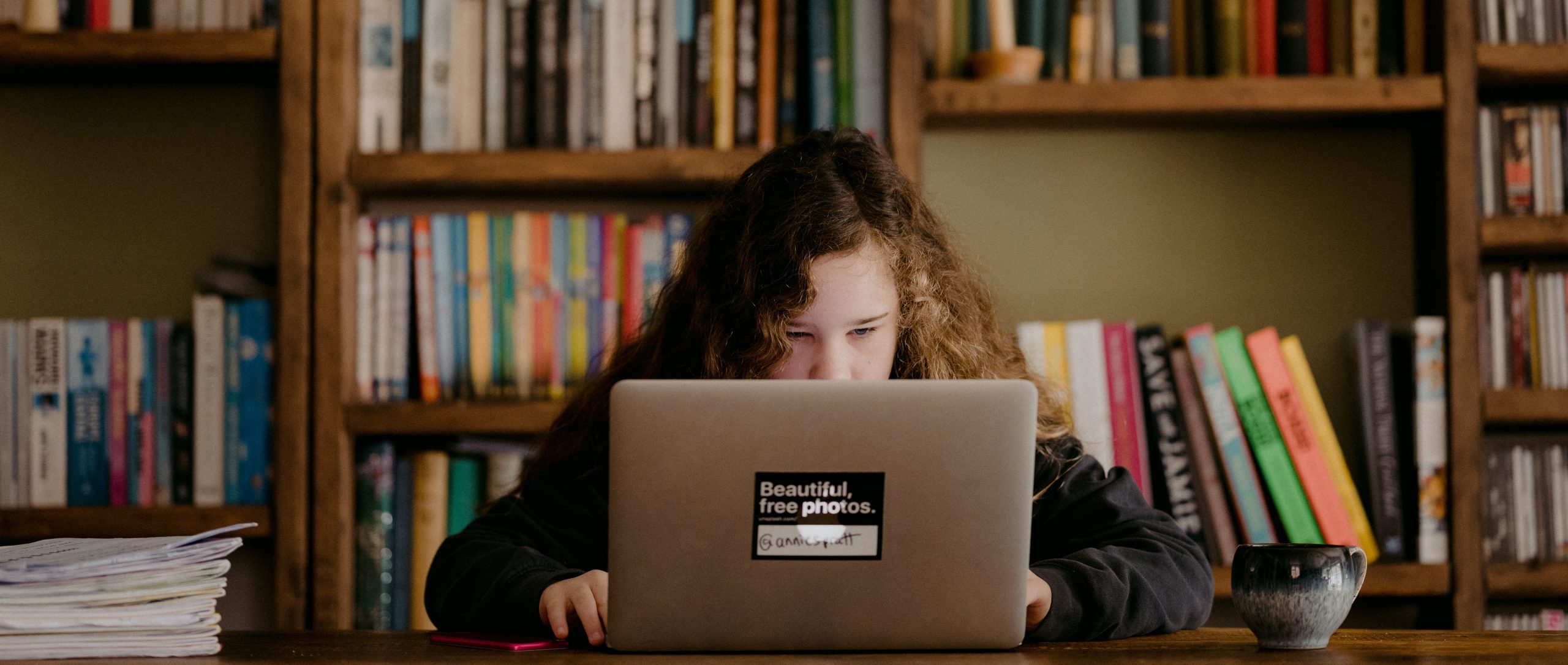 Child on laptop in front of a bookcase
